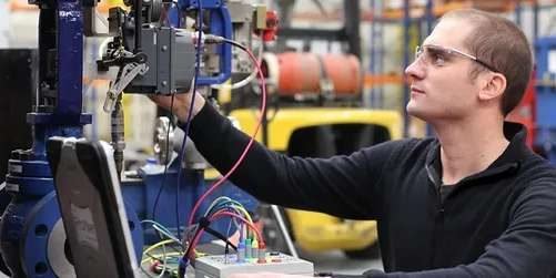 Technician commissioning an antisurge valve positioner in a workshop
